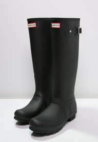 Schwarze Gummiregenstiefel in knielanger Ausführung mit abgerundeter Spitze, strukturiertem Obermaterial, verstellbarem Schnallendetail und robuster, profiliertem Sohle.