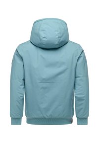 Ljusblå huvjacka med en slät yta, ribbade ärmslut och fåll. Har en enkel, minimalistisk design utan synliga stängningar.