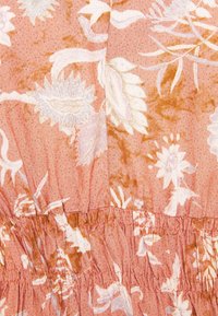 Blommig tyg i dämpad rosa med vita och oranga mönster. Strukturerad med samlingar i midjan, vilket skapar en lager-effekt.