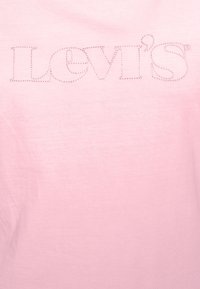 Růžové bavlněné tričko se vyšitým logem Levi's v mírně tmavší růžové barvě. Hladká textura s krátkými rukávy a designem s kulatým výstřihem.