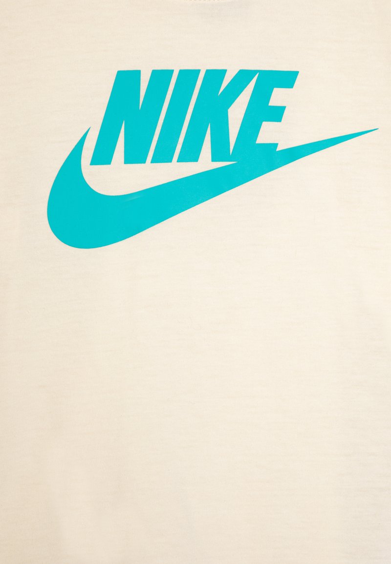 Crème-kleurig t-shirt met een groot, turquoise Nike-logo en een gebogen accentgrafiek, gemaakt van zacht katoen.