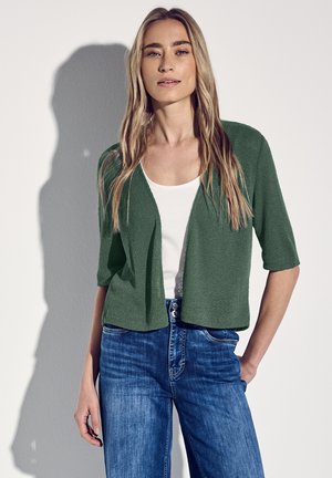 Green open-front cardigan with short sleeves, paired with a white top and blue jeans. Textured knit fabric. Simple design, casual fit.