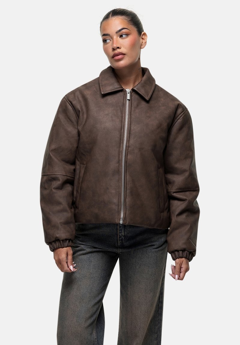 Giubbotto bomber in finta pelle marrone con zip frontale, grande colletto, polsini elasticizzati e tasche laterali. Presenta una superficie liscia e opaca.