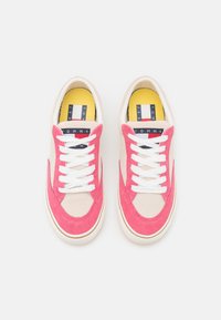 Sneaker in suede rosa e beige con lacci bianchi, punta tondeggiante e soletta gialla con stampa del logo. Suola in gomma con grip texture.