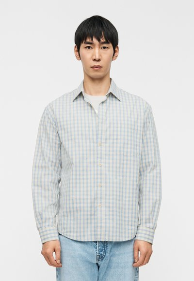 Chemise à carreaux bleu clair et crème avec des boutons sur le devant, manches longues et une poche poitrine, en tissu de coton léger.