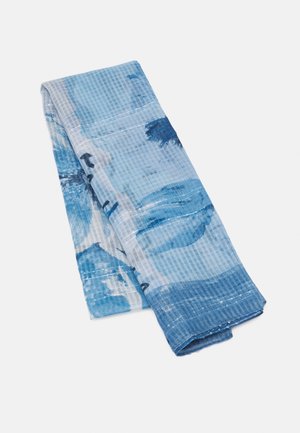 Écharpe pliée bleue et blanche à motifs avec des formes abstraites et des lignes texturées subtiles sur un fond blanc uni.