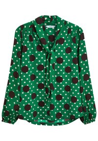 Grøn bluse med sorte og hvide polkadots, lange ærmer med sammensnørrede manchetter, og en løs pasform med knydebånd ved halsen.