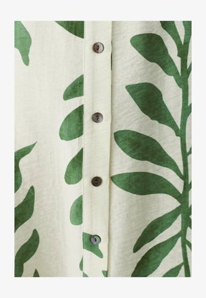Látka s potiskem zelených listů na béžovém pozadí, se zaoblenými hnědými knoflíky podél středového zapínání. Lehký, strukturovaný materiál.