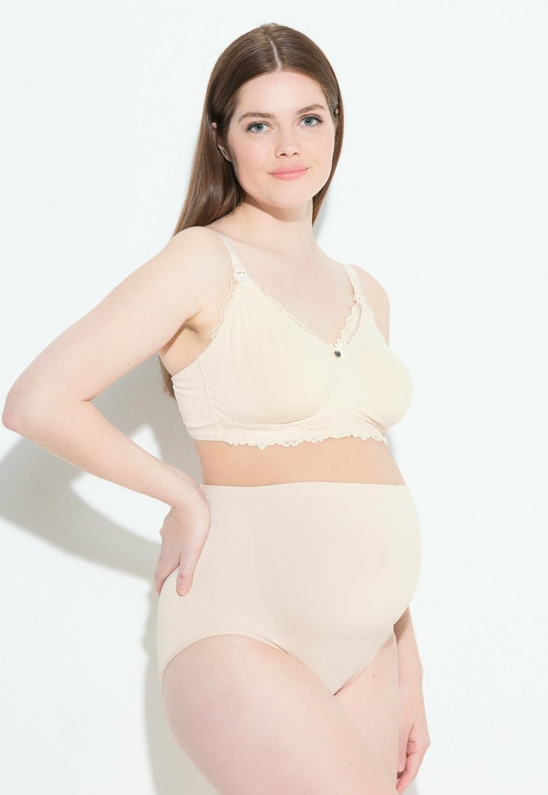 Bralette per maternità nuda con bordo in pizzo e bottone centrale, abbinata a slip alti nudi. Tessuto morbido e elastico per il comfort.