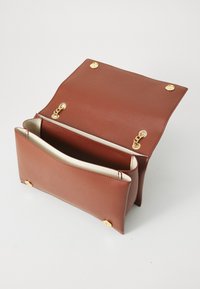 Braune Ledertasche mit goldenen Magnetschnappverschlüssen und Kettenelementen, geöffnet, um zwei Hauptfächer mit cremefarbener Innenausstattung zu zeigen.