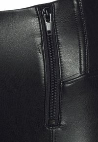 Schwarzes Leder mit sichtbarem Reißverschluss-Detail. Verfügt über eine strukturierte Oberfläche und genähte Akzente entlang der Kanten.