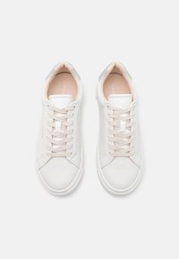 White leather sneakers with a textured surface, round toe, and beige laces. Silver accent on the heel and simple branded interior detail.