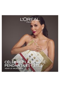 Le coffret cadeau de beauté L'Oréal Paris se présente dans un emballage doré, orné d'un design festif avec des accents décoratifs et un grand ruban rouge.