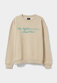 Felpa beige dal taglio rilassato. Presenta un testo turchese che recita "Los Angeles È SEMPRE UNA Buona Idea" sulla parte anteriore.