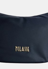 Borsa a spalla in nylon blu navy con una texture liscia e un accento del logo in tono oro. Design minimalista con forma arrotondata.