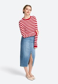 Rot-weißer gestreifter Langarmshirt, kombiniert mit einem hellblauen Jeansrock mit Schlitz vorne, abgerundet durch beigen Ballerinas.
