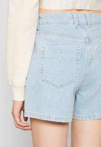 Light blue denim shorts with a frayed hem, two back pockets, and a mid-rise fit. The fabric has a soft, faded texture.