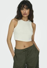 Witte, geknipte mouwloze tanktop met een ribbelstructuur, met een ronde halslijn. Gecombineerd met olijfgroene broek met verstelbare taille. 