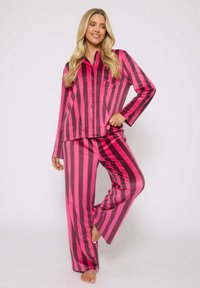 Roze en donkergrijze gestreepte pyjama set van gladde stof, bestaande uit een knoopsluitingen lange mouwen top en bijpassende wijde broek.