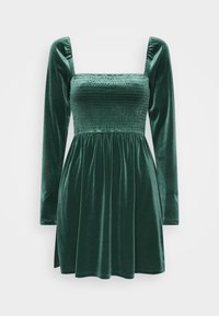 Robe en velours vert avec un corsage ajusté à smocks, décolleté carré et longues manches bouffantes ; jupe évasée avec des plis pour plus de volume.