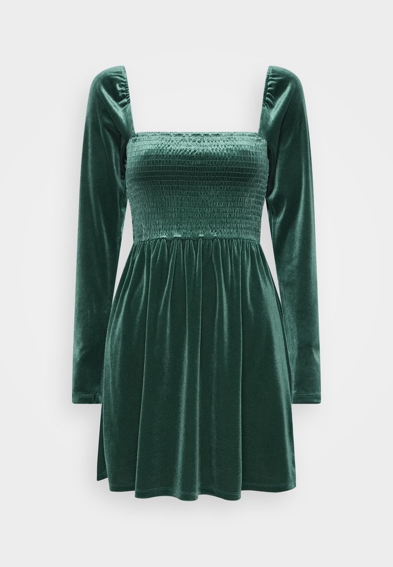 Robe en velours vert avec un corsage ajusté à smocks, décolleté carré et longues manches bouffantes ; jupe évasée avec des plis pour plus de volume.