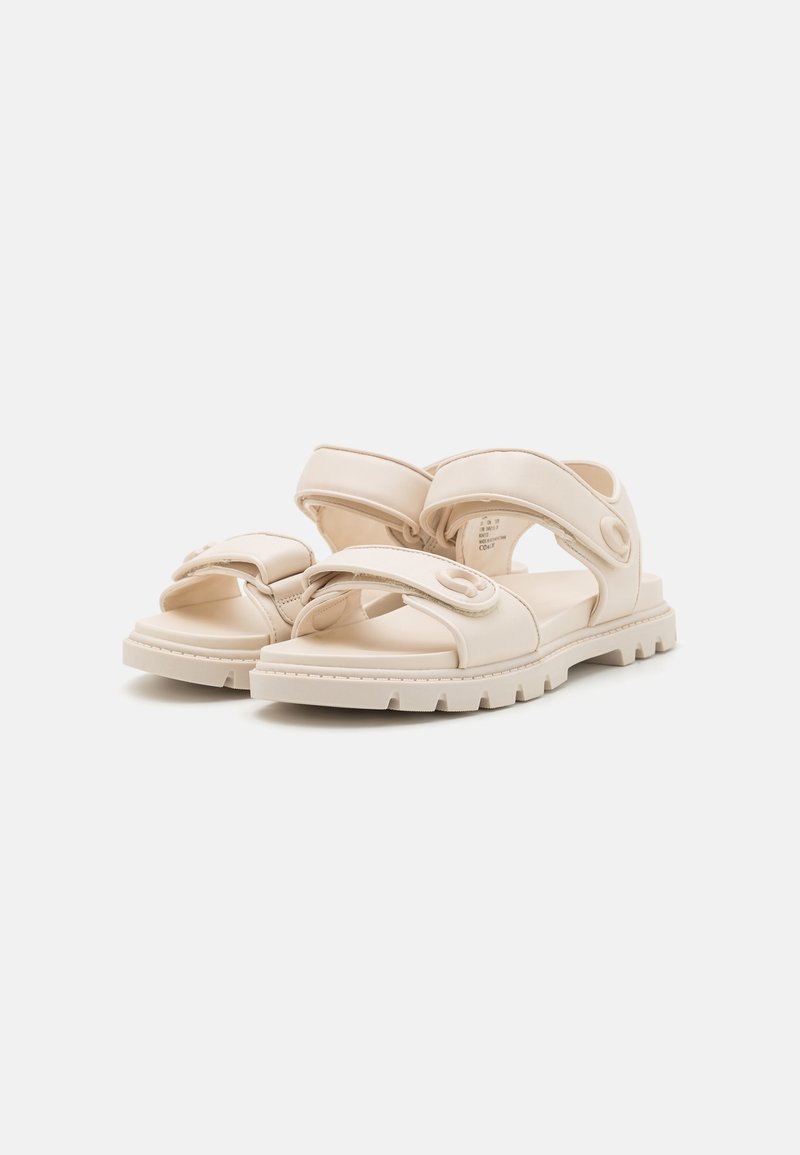 Beżowe sandały z grubą podeszwą, wieloma szerokimi paskami, teksturowanymi akcentami oraz wygodną wkładką z regulowanymi zapięciami.