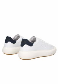 Sneaker bianche con tomaia in pelle liscia, laccio posteriore in camoscio blu navy, suola intermedia spessa color crema e suola in gomma. Marchio impresso di lato.