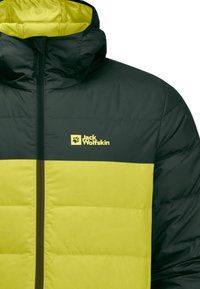 Giacca isolante verde e gialla con cappuccio, dotata di chiusura con zip e logo sul petto. Design imbottito con blocchi di colore a contrasto.