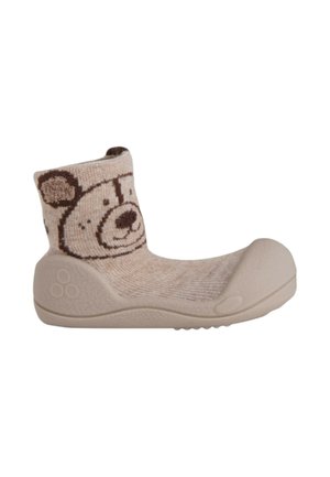 Calcetín-zapato beige para niño pequeño con suela de goma y una cara de oso sonriente tejida en el puño del tobillo.