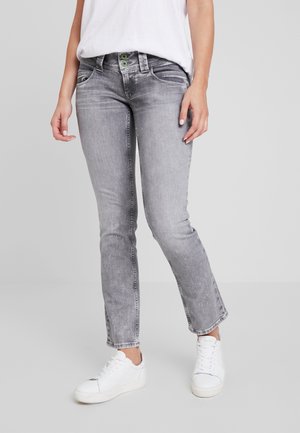 Grå denimjeans med slim fit, med en klassisk femfickdesign och knappstängning, försedda med gröna knapppunkter och vita sneakers.