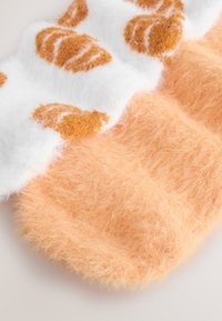 Oranžid, kohevates sokkides pehme tekstuuriga. Ülaservas on valged pruunide croissantimustritega, mis üleminevad allosas ühtlase oranži tooniga.