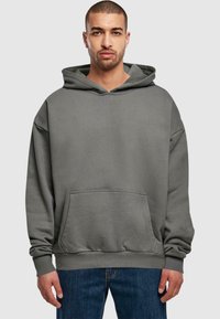 Felpa grigia con cappuccio, caratterizzata da una tasca frontale, una vestibilità comoda e polsini a coste, abbinata a jeans in denim blu.