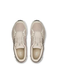 Beige running shoes with mesh upper, padded tongue, and elastic laces. Thick sole with textured accents and logo on insole.