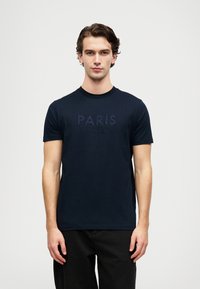 Jūras zila kokvilnas T-kreklu ar īsām piedurkn�ēm, apaļu kakla izgriezumu, ar izšūtu tekstu "PARIS" un "KARL LAGERFELD" kontrastējošā tumši zilā krāsā.