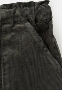 Tummat vakosamettihousut, joissa on uritettu pinta, elastinen vyötärö ja viistot etutaskut. Kangas näyttää pehmeältä ja siinä on hieman kiiltoa.