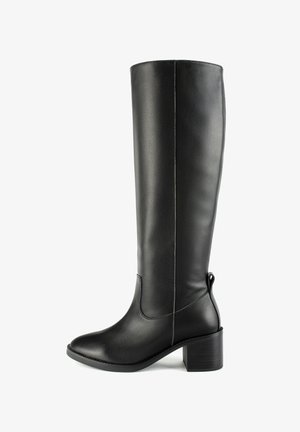 Botte en cuir noir montante avec un léger talon, texture lisse, bout pointu et coutures minimales. Elle comporte une poignée à l'arrière.