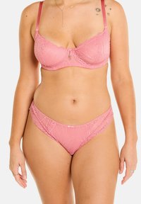 Ensemble soutien-gorge et slip en dentelle de couleur rose doux, avec des motifs floraux, des bords festonnés et un charme décoratif central sur le soutien-gorge.