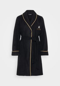 Čierny fleece župan so zlatým lemovaním, s šálovým golierom a viazaním v páse. Obsahuje prednú vrecko s vyšívaným logom. Mäkká textúra.