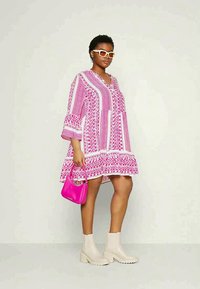 Ροζ φόρεμα με σχέδιο και τρία τέταρτα μανίκια, σε συνδυασμό με μια ταιριαστή ροζ τσάντα ώμου και μπεζ μποτάκια μέχρι τον αστράγαλο. Διαθέτει V-υποδημα.