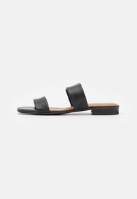 Svart platt sandal med två breda remmar, öppen tå och låg klack, visad mot en vit bakgrund.
