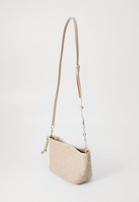 Beige crossbody veske laget av teksturert materiale med et dekorativt mønster, justerbar stropp og detaljer i gullfarge.