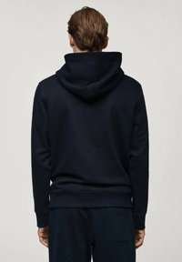 Námornícky modrá mikina s klokaním vreckom a šnúrkou na kapucni. Vyrobená z mäkkej tkaniny, má rebrované manžety a voľný strih.