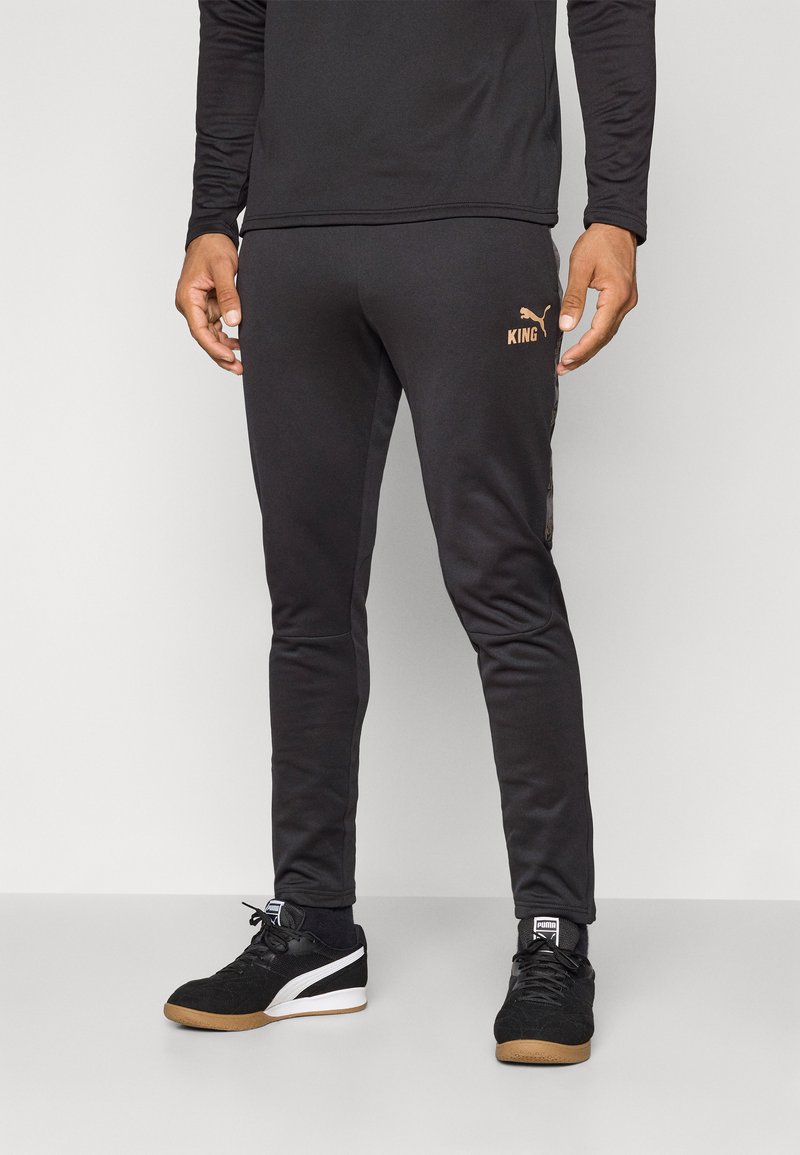 Melni sporta bikses ar slaidu piegriezumu, ar zeltītu logotipu "KING" un elegantiem sānu paneļiem. Saskaņotas ar melniem sporta apaviem.