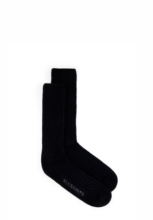 Sorte ribbede sokker lavet af tykt stof, med en ensfarvet overflade og et logo trykt på sålen. Glat tekstur og design der går op til knæet.