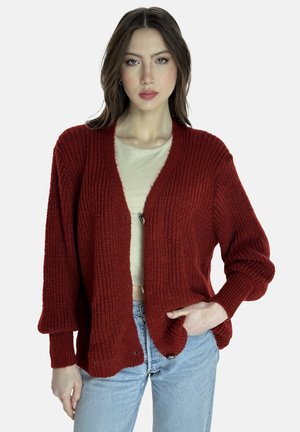 Roter strukturierter Cardigan mit langen Ärmeln, offener Vorderseite und einer einzelnen Knopfverschluss, getragen über einem hellbeigen Oberteil und blauen Jeans.