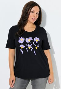 Czarny t-shirt z krótkim rękawem z kwiatowym wzorem z lawendowych stokrotek z żółtymi środkami, wykonany z miękkiego bawełnianego materiału.