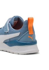 Helle blaue Sneaker aus Netz- und Synthetikmaterialien, mit einer weißen Sohle, einem orangefarbenen Fersenriemen und dem orangefarbenen Puma-Logo an der Seite.