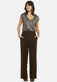 Top grigio lucido a maniche corte con scollo a V, abbinato a pantaloni marrone scuro a gamba larga a vita alta con tasche frontali e chiusura con bottoni.