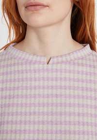 Hellblau kariertes Strickoberteil mit V-Ausschnitt und subtiler Textur. Aus weichem, angenehmem Material und in lockerer Passform.