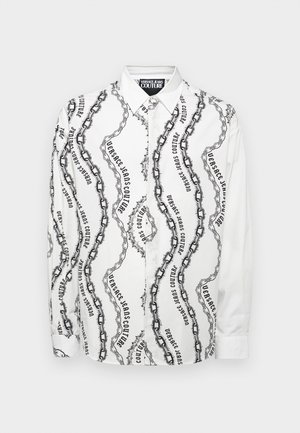 Dolga majica z dolgimi rokavi iz belega bombaža s črnim vzorcem verige in besedila. Ima klasičen ovratnik in zapiranje na gumb.